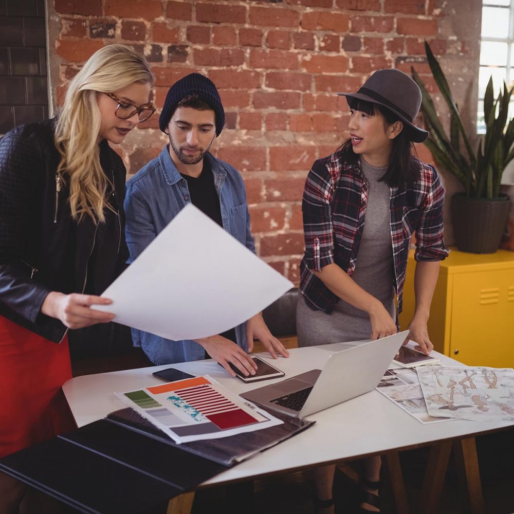 young-creative-team-discussing-over-papers-at-coff-S3T26FQ.jpg